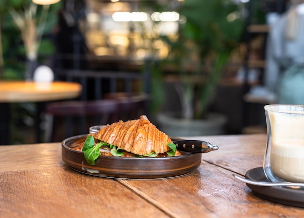 Petit-déjeuner avec croissant sandwich au fromage et salade à la sauce tomate et café au café