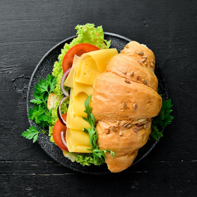 Petit-déjeuner croissant sandwich au fromage tomates et oignons Vue de dessus Espace libre pour votre texte