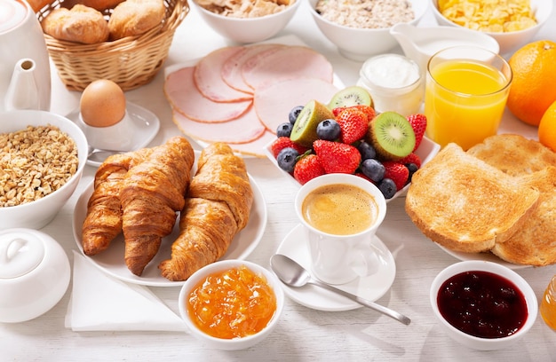 Petit déjeuner avec croissants café jus viande confiture céréales et fruits frais