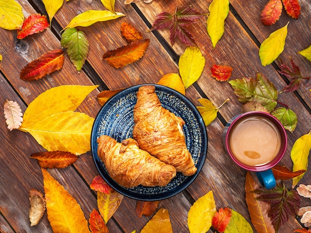 Photo petit-déjeuner dans le jardin un jour d'automne café avec crème et croissants