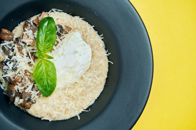 Un petit déjeuner délicieux et sain. Flocons d'avoine avec œuf poché, parmesan et champignons dans une assiette noire sur s