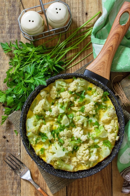 Photo petit-déjeuner diététique ou déjeuner sain omelette aux œufs avec chou-fleur dans une casserole sur une table en bois rustique