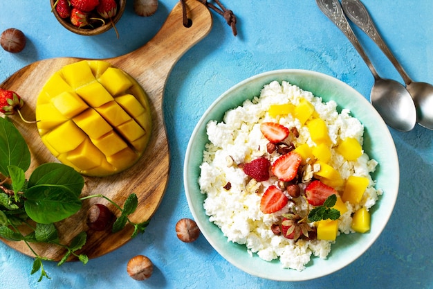 Petit-déjeuner diététique pour l'heure d'été Fromage cottage frais avec fraise, mangue et noix Vue de dessus