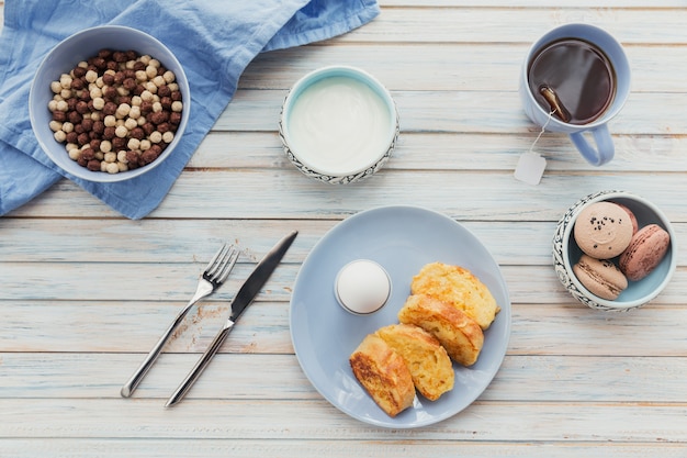 Petit-déjeuner avec du yogourt aux croûtons frits et du thé noir sur une surface en bois clair