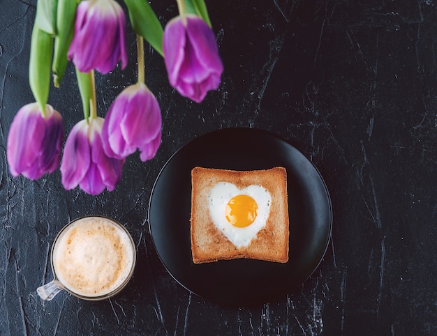 Petit-déjeuner encore pour un être cher avec des tulipes sur fond sombre