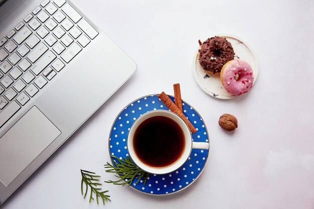 Petit-déjeuner esthétique à la maison avec une tasse de café, des beignets et un ordinateur portable