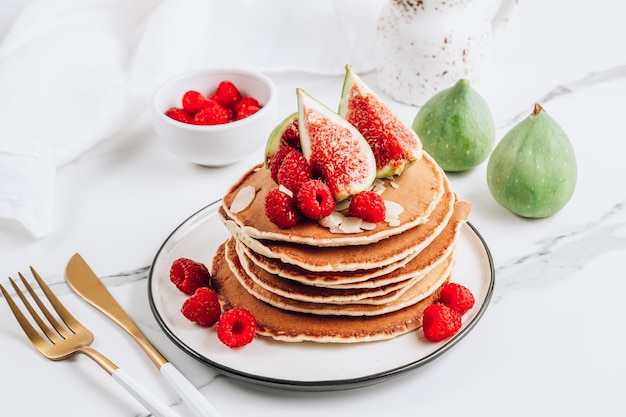 Petit-déjeuner d'été crêpes américaines classiques faites maison avec des framboises fraîches aux amandes et des figues Fond en marbre blanc Mise au point sélective