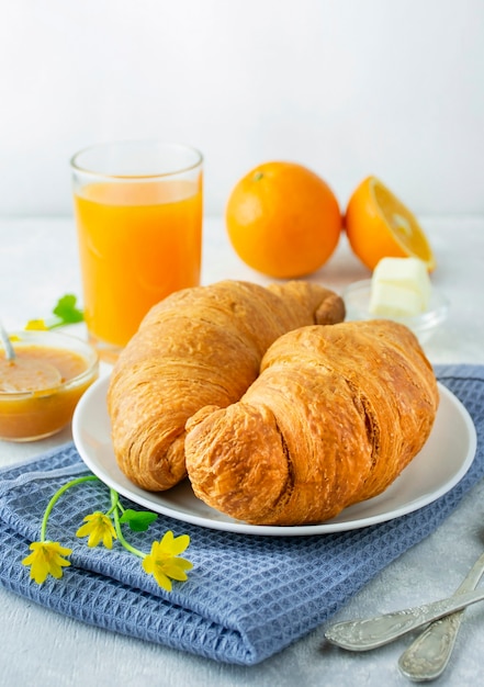 Petit déjeuner européen avec croissants frais, confiture et jus d'orange. Petit-déjeuner sur une table lumineuse, vue latérale. Fond de nourriture.