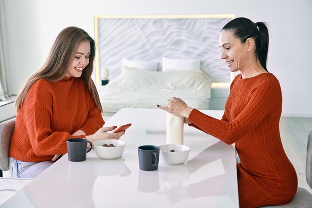 Petit-déjeuner familial des femmes mère et fille s'assoient à la table à manger dans la cuisine et préparent des céréales pour le petit-déjeuner