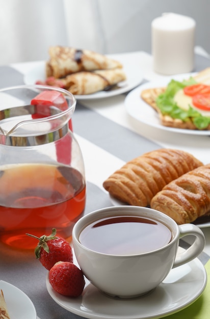 Petit déjeuner frais et savoureux avec thé et brioches sur un fond clair.
