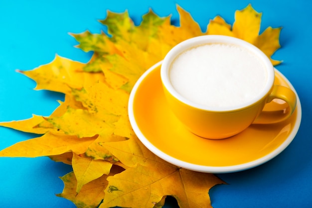 Petit déjeuner français. belle tasse de café jaune cappuccino avec croissant sur fond bleu