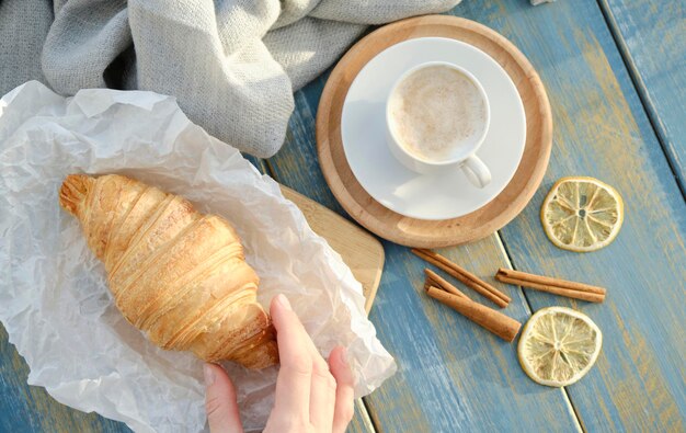 Petit-déjeuner français avec croissants et café sur fond de bois.