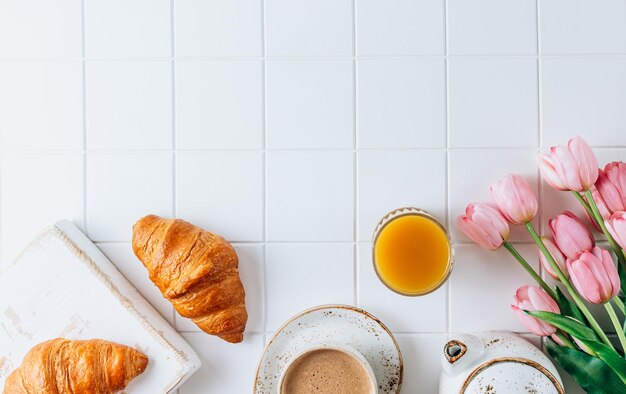 Petit déjeuner français avec croissants jus d'orange et café aux tulipes roses