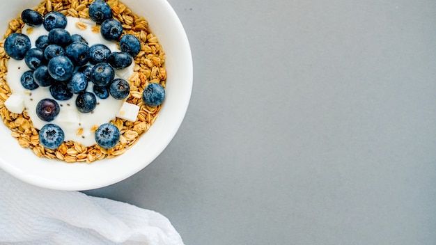 Petit-déjeuner granola avec petit-déjeuner granola aux bleuets sur un torchon blanc sur fond gris clair sur une table