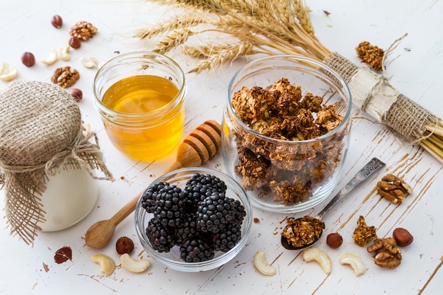 Petit déjeuner - granola, yaourt, baies, noix, miel, blé