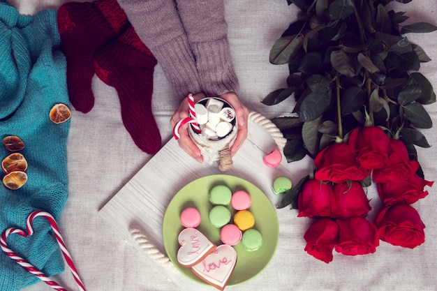 Petit déjeuner d'hiver au lit avec des roses rouges et coeur de sucette à rayures