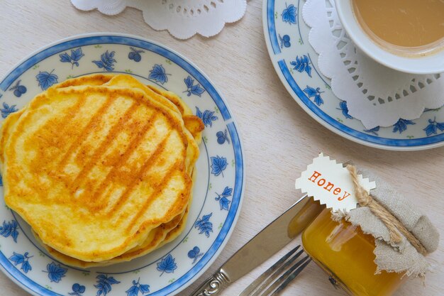 Petit déjeuner d'hiver : crêpes au fromage avec du miel et une tasse de cappuccino