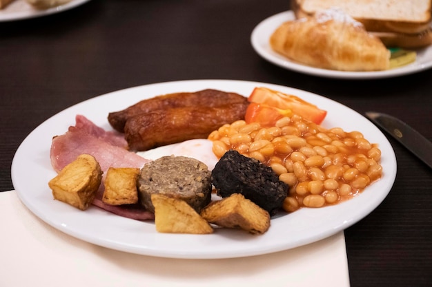 Petit-déjeuner irlandais avec haricots sucrés tomates saucisses pommes de terre bacon à l'hôtel