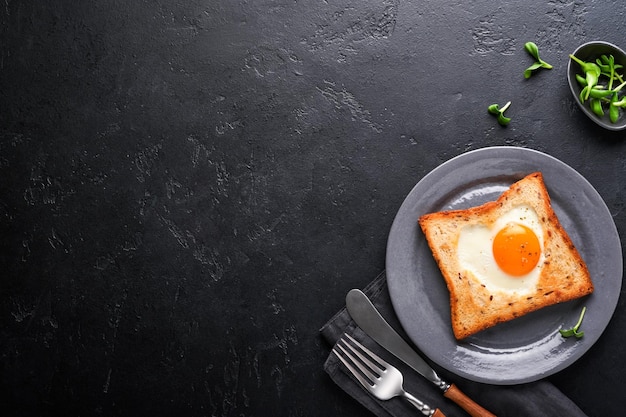 Petit-déjeuner le jour de la Saint-Valentin Œufs frits et pain en forme de cœur et légumes frais sur fond noir Petit-déjeuner avec surprise pour les proches Vue de dessus Maquette