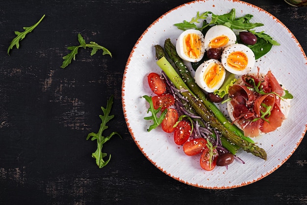 Petit-déjeuner Keto Asperges frites avec des œufs durs et du pain grillé avec du prosciutto ou du jamon Régime cétogène Alimentation saine Vue de dessus mise à plat