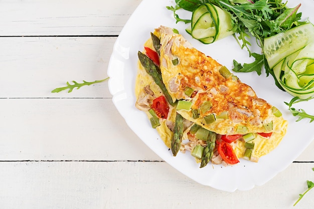 Petit-déjeuner Keto Omelette avec filet de poulet tomates et asperges sur une table en bois blanche Frittata italienne Déjeuner cétogène Keto Vue de dessus espace de copie au-dessus