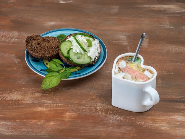 Un petit-déjeuner léger avec café et sandwich sur pain de seigle avec fromage à pâte molle et concombre au basilic l