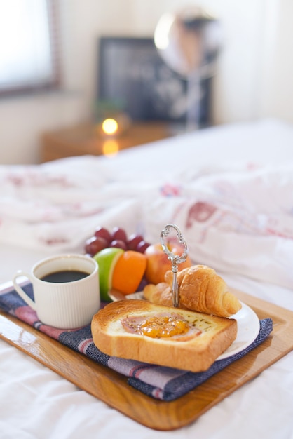 Photo petit déjeuner sur le lit avec café, croissants
