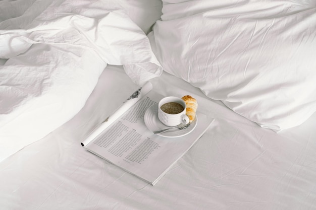 Petit-déjeuner sur le lit dans la chambre d'hôtel petit-déjeuner dans un lit blanc comme neige café avec un croissant