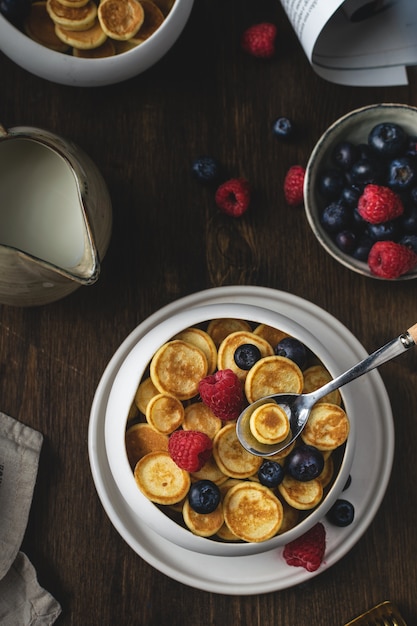 Photo petit-déjeuner maison branché, céréales à crêpes, mini-crêpes aux fruits rouges, vue de dessus