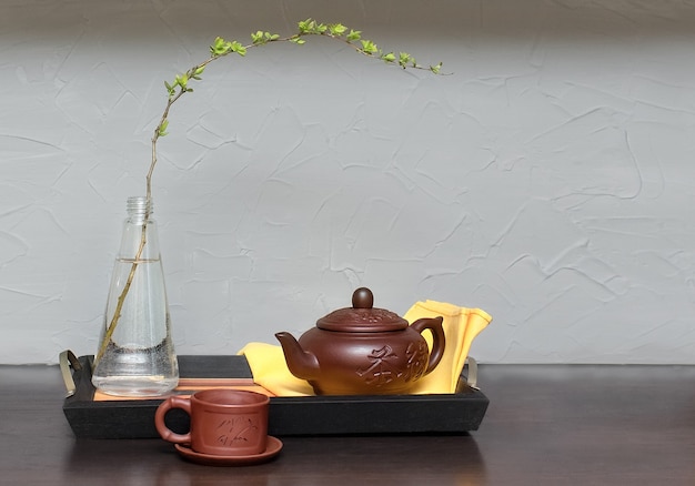 Petit déjeuner à la maison. Une branche dans une bouteille sur un plateau, un livre, une théière et une serviette