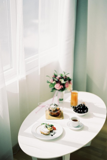 Le petit-déjeuner de la mariée se dresse sur une table blanche servie près de la fenêtre
