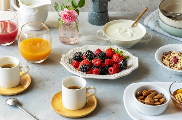 Photo petit-déjeuner le matin avec baies muesli café lait yaourt miel amandes et jus