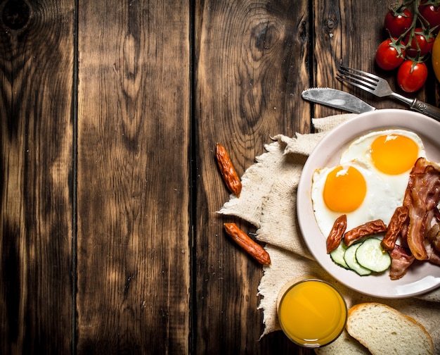 Petit-déjeuner Le Matin Du Bacon Frit Avec Des œufs Et Du Jus D'orange Sur Une Table En Bois