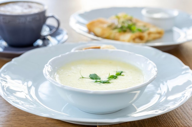 Petit-déjeuner matinal avec soupe au fromage croûtons au café crêpes et légumes verts sur fond de rétro-éclairage