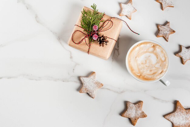 Petit déjeuner de Noël, tasse de café avec des biscuits en pain d'épice, avec un cadeau de Noël ou un cadeau, sur une table en bois blanche vue de dessus copyspace