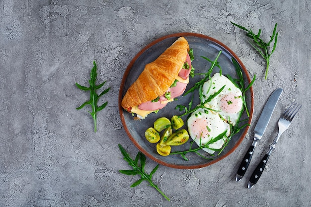 Petit-déjeuner avec œufs au plat et croissant avec du jambon, du fromage et de la salade Délicieux petit-déjeuner matinal Vue de dessus