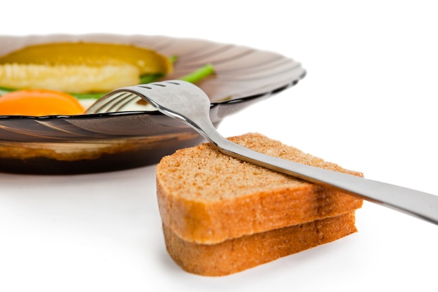 Petit déjeuner Oeufs au plat sur une plaque de verre, avec un concombre mariné, des oignons frais et du pain de seigle