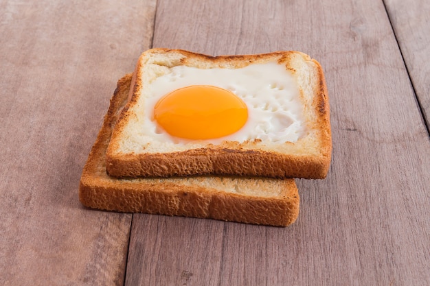 petit-déjeuner avec des œufs au plat, des toasts sur une table en bois.