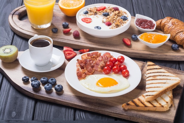 Petit-déjeuner avec des œufs au yaourt, des baies, du jus, du croissant et de la confiture