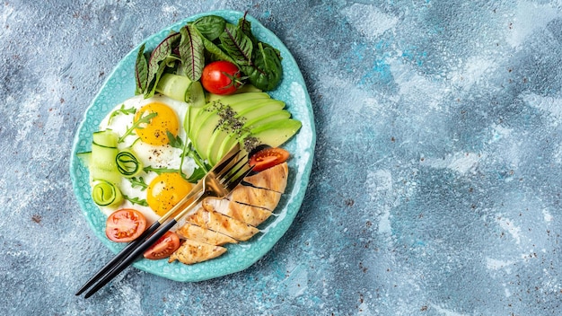 Petit-déjeuner Oeufs d'avocat Tomates cerises Filet de poulet grillé Concombres Petit-déjeuner régime cétogène Place pour le texte Vue de dessus