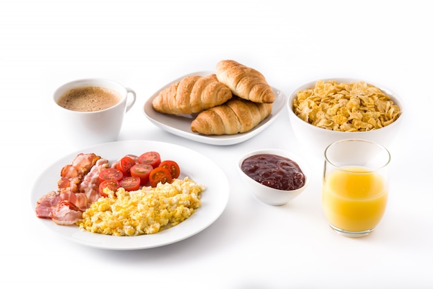 Petit-déjeuner avec œufs brouillés, bacon, tomates, café, jus d'orange, croissant et flocons de maïs isolés sur blanc