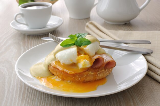 Petit déjeuner d'oeufs durs (pochés) avec du jambon sur un petit pain à la sauce moutarde