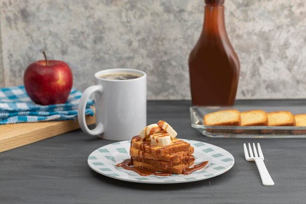 Petit déjeuner de pain grillé avec cajeta et banane accompagné d'une tasse de café et pomme