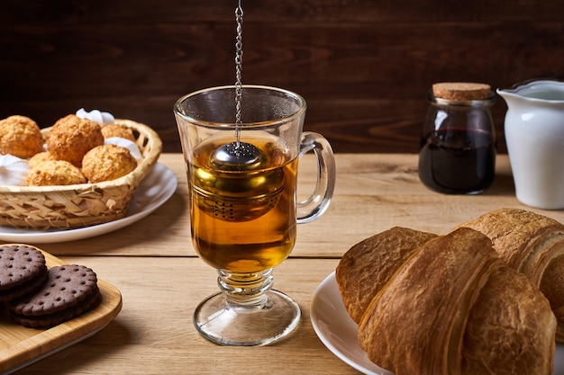 Petit-déjeuner avec passoire à thé et bonbons sur table en bois