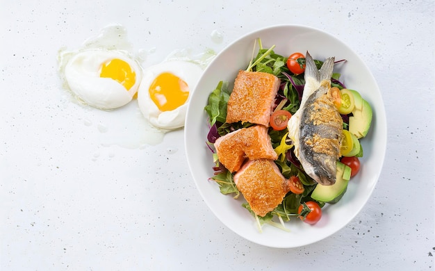 Petit-déjeuner à régime cétogène Saumon salé et salade dorado cuite au four avec des légumes verts tomates œufs et avocado