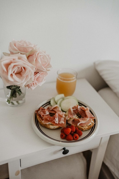 Petit-déjeuner sain au lit avec des fleurs. Esthétique