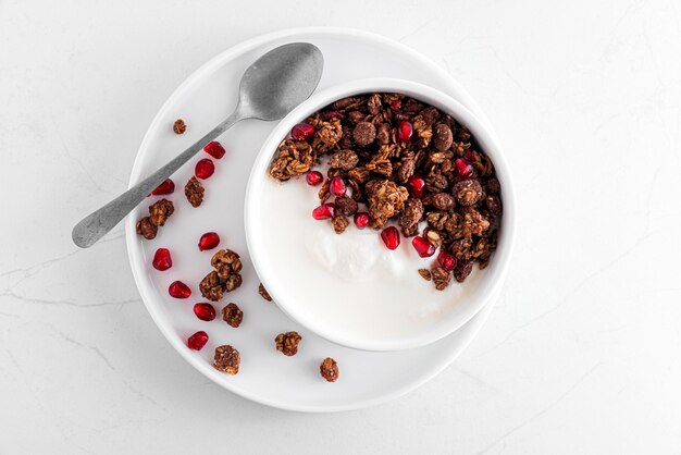 Petit-déjeuner sain Bol de yaourt grec avec granola d'avoine au chocolat et graines de grenade sur table en marbre blanc