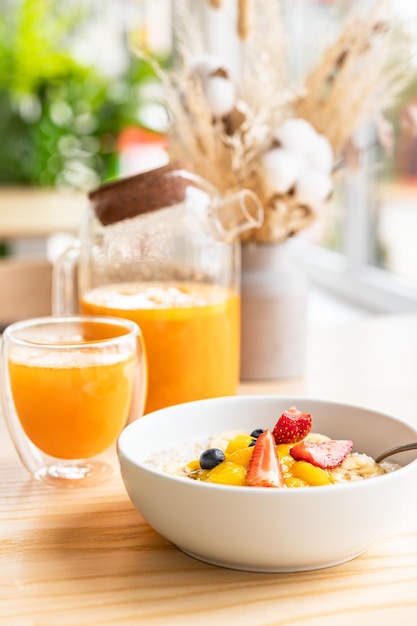 Petit-déjeuner sain avec bouillie d'avoine aux baies banane et mangue et thé épicé à l'argousier