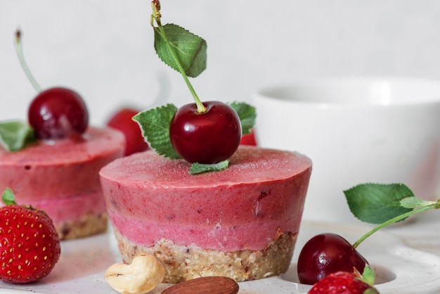 Petit-déjeuner sain. cheesecakes maison aux fraises et cerises avec des baies fraîches, de la menthe, des noix et une tasse de café. nourriture végétalienne