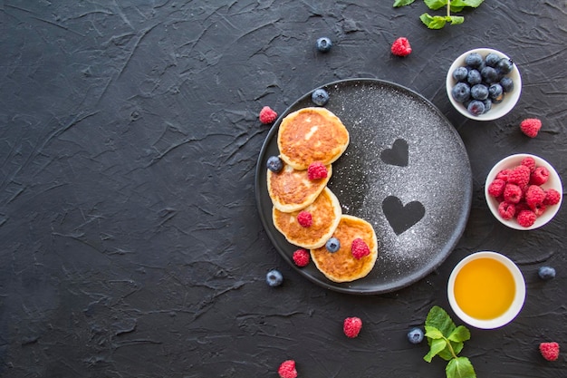 Un petit-déjeuner sain composé de crêpes au fromage, de baies et de miel. Décoration d'ambiance créative